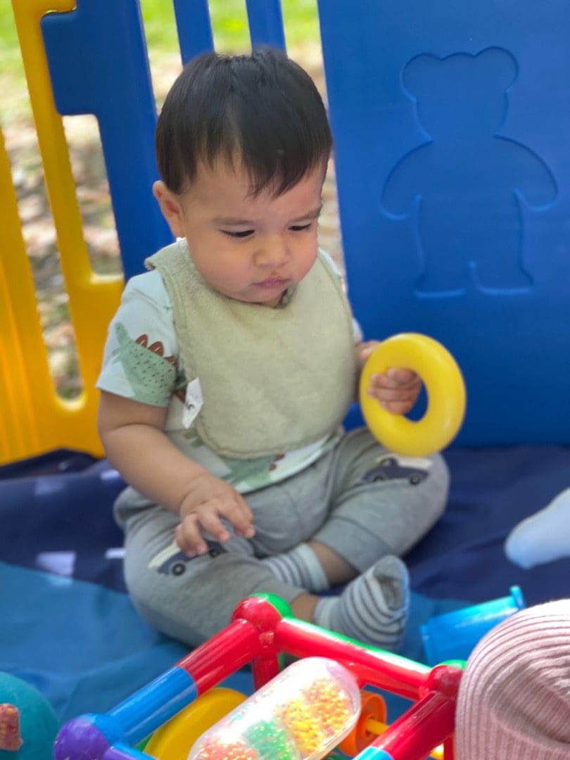 A baby sitting on the ground playing with toys.
