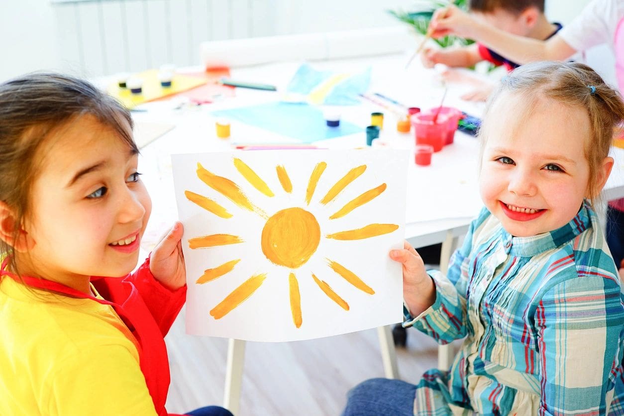 Two children holding up a picture of the sun.